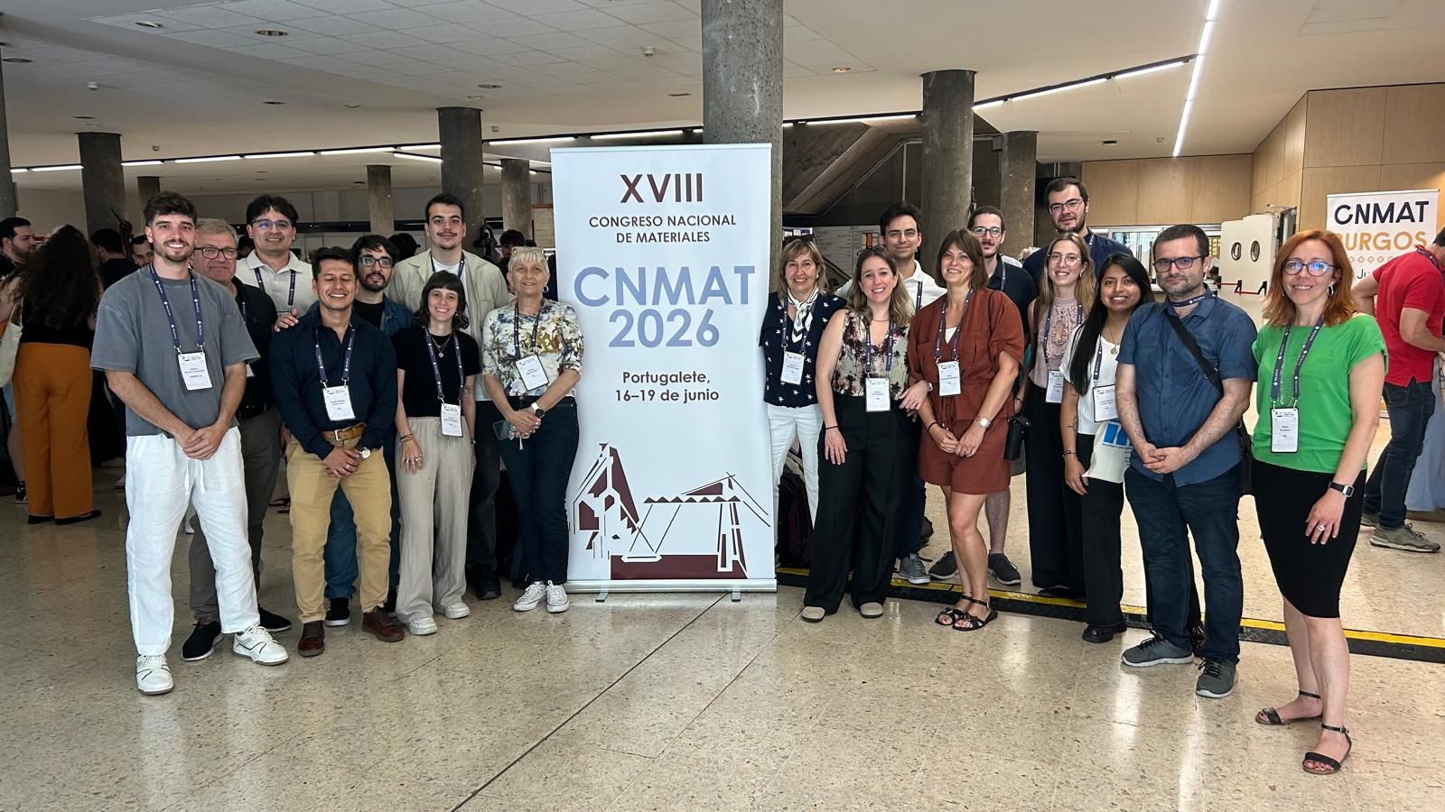 Equipo de DIOPMA junto al cartel del XVIII Congreso Nacional de Materiales (CNMAT 2026) en Portugalete.